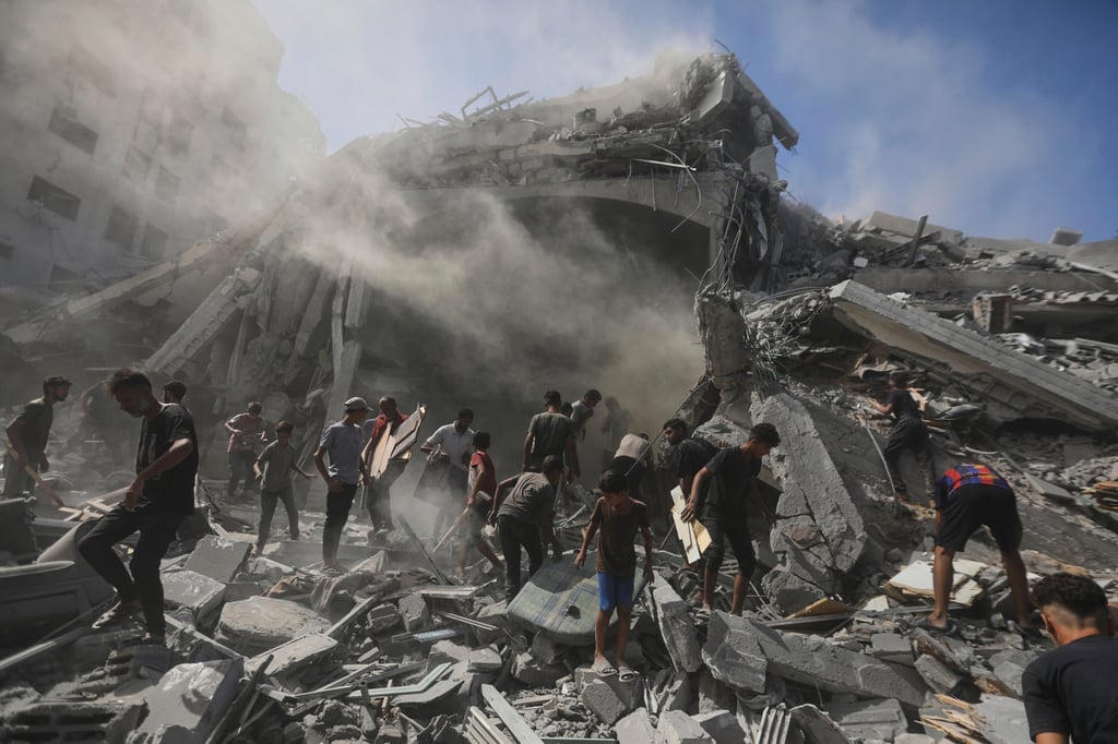Palestinians search for wood on Sunday to sell or use for cooking amid the rubble of a building destroyed in an Israeli military strike in Gaza City. Photo: AP Palestinians search for wood on Sunday to sell or use for cooking amid the rubble of a building destroyed in an Israeli military strike in Gaza City. Photo: AP