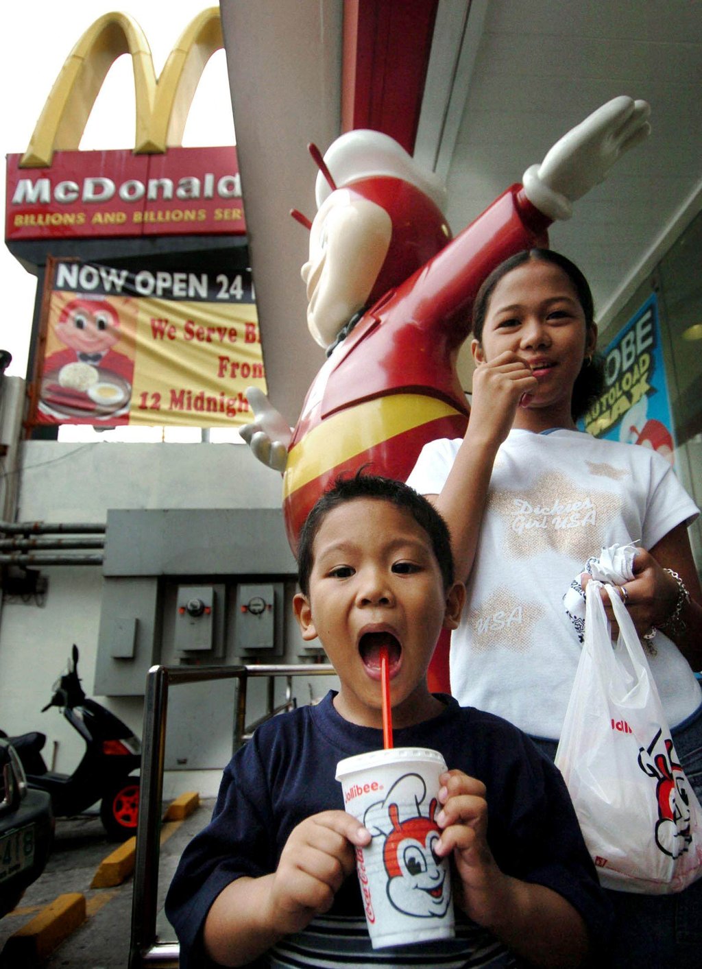 Children enjoy Jollibee snacks outside an outlet in Manila with a McDonald's logo in the background. Photo: AFP Children enjoy Jollibee snacks outside an outlet in Manila with a McDonald's logo in the background. Photo: AFP